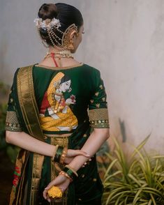 a woman in a green sari with gold jewelry on her neck and hands behind her back