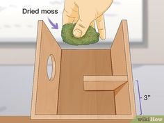 a hand is cleaning the bottom of a wooden box with a green rag on it