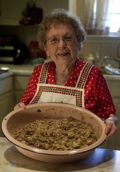 an elderly woman holding a large dish of food