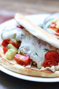 a pita sandwich with tomatoes, cucumbers and sour cream sauce on it