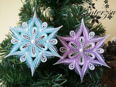 two paper snowflakes sitting on top of a christmas tree