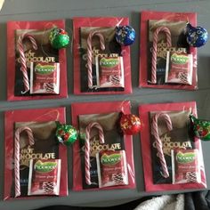 chocolate candies and candy canes are displayed on red paper bags in front of a gray wall