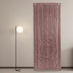 an empty room with a pink curtain on the wall next to a black floor lamp