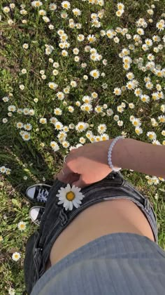 a person standing in front of a field of daisies with their hand on the ground