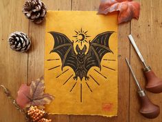 a paper with a bat on it next to some pine cones and other autumn decorations