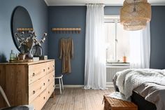 a bedroom with blue walls and white curtains