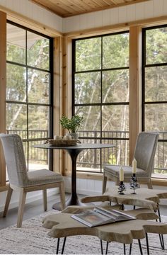 a living room filled with furniture and large windows next to a table surrounded by chairs