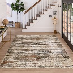 an area rug in the middle of a living room with stairs leading up to it