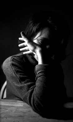 a woman sitting at a table with her hands on her face