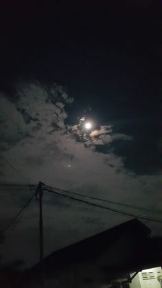 the full moon is shining brightly in the night sky over some houses and power lines