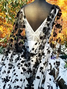 a black and white dress on display in front of a brick wall, with flowers all over it