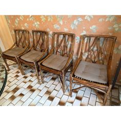 four wooden chairs sitting next to each other on a tiled floor