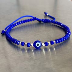 a blue bracelet with an evil eye beaded on it, sitting on a table