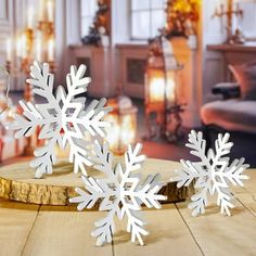 three white snowflakes sitting on top of a wooden table