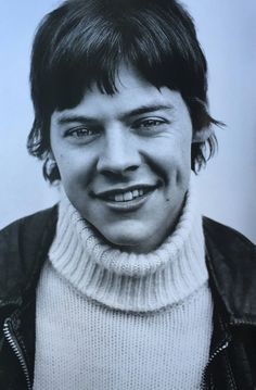 an old photo of a young man with a smile on his face and wearing a leather jacket