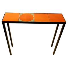 an orange table with two legs and a circular design on the top, against a white background