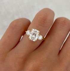 a woman's hand with a diamond ring on top of her finger and two diamonds in the middle