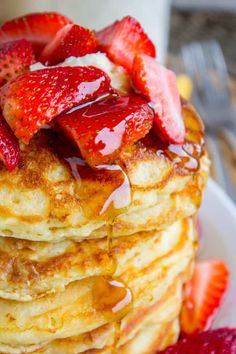 a stack of pancakes covered in syrup and strawberries