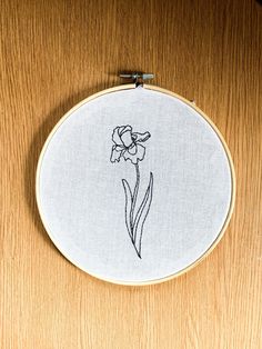 a white embroidery with a flower on it sitting on top of a wooden table next to a pair of scissors