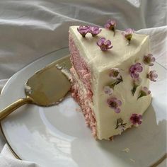 a piece of cake with white frosting and pink flowers on it is sitting on a plate