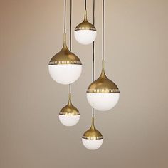 three light fixtures hanging from a ceiling with white and gold shades on them, in an empty room