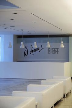 an empty waiting area with white chairs and lights hanging from the ceiling, in front of a wall that reads we speak