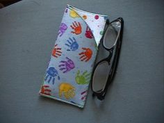 a pair of black glasses sitting on top of a table next to a handprinted pouch