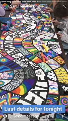 people are sitting at a long table painted with colorful images and text that reads last details for tonight