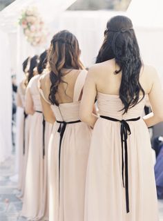 the bridesmaids are wearing long dresses with black bows on their waists and back