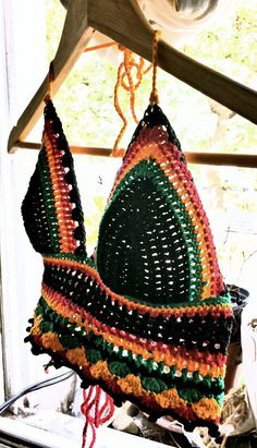 a crocheted hat hanging from a wooden hanger on a window sill