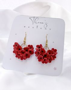 a pair of red flower earrings sitting on top of a white card with the tag