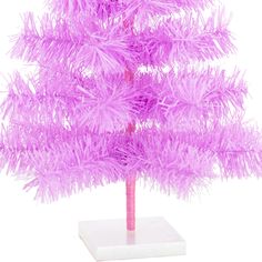 a small purple christmas tree on a white base with pink feathers in the shape of a pine