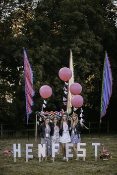 three girls standing in front of a sign with balloons and streamers on it that says henfest