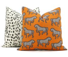 two pillows with different animal designs on them, one in orange and the other in black