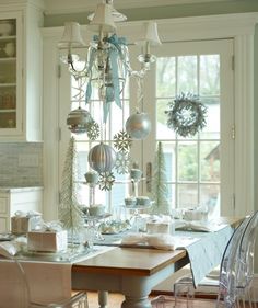 a dining room table with christmas decorations and ornaments hanging from it's centerpiece