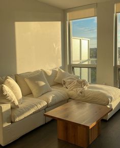 a living room filled with white furniture and large windows overlooking the cityscape in the distance