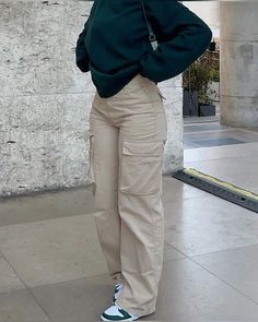 a woman standing in front of a building with her hands on her hips and looking off to the side