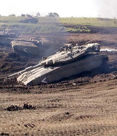 two tanks sitting on top of a dirt field