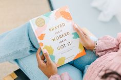 a woman sitting on a couch holding a book that reads, prayed for it worked for it got it