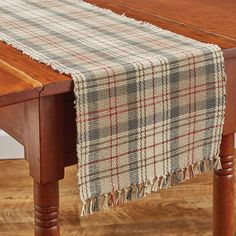 a plaid table runner is on top of a wooden dining room table with wood legs