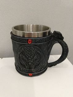 a metal cup sitting on top of a white table next to a black snake handle