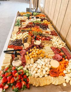 a long table filled with lots of different types of cheeses and crackers on it