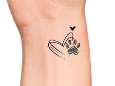 a small tattoo on the wrist of a woman's arm with a dog paw and heart