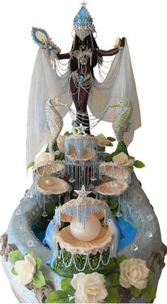 a statue is displayed on top of a fountain with water and flowers around it in front of a white background