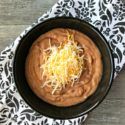 a black bowl filled with hummus and cheese on top of a white and black napkin