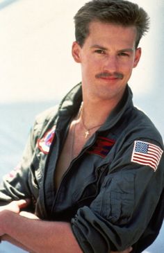 a man with a moustache and an american flag on his shirt is posing for a photo