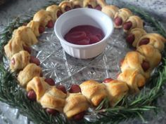 a platter with pigs in a blanket on it and a small bowl of jelly