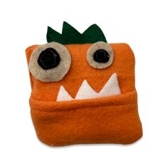 an orange stuffed animal with big eyes and a green leaf on it's head