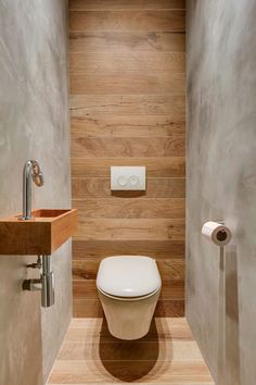 a bathroom with a toilet, sink and wood paneling on the wall behind it