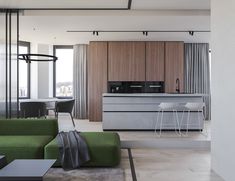 an open concept kitchen and living room with green couches in the foreground, large windows to the right